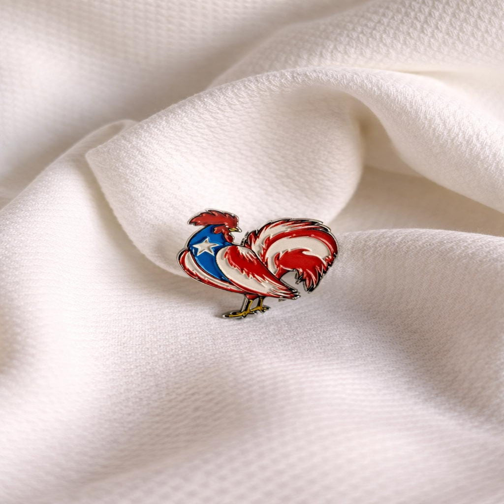 Colorful rooster-shaped pin on a white fabric background Main image